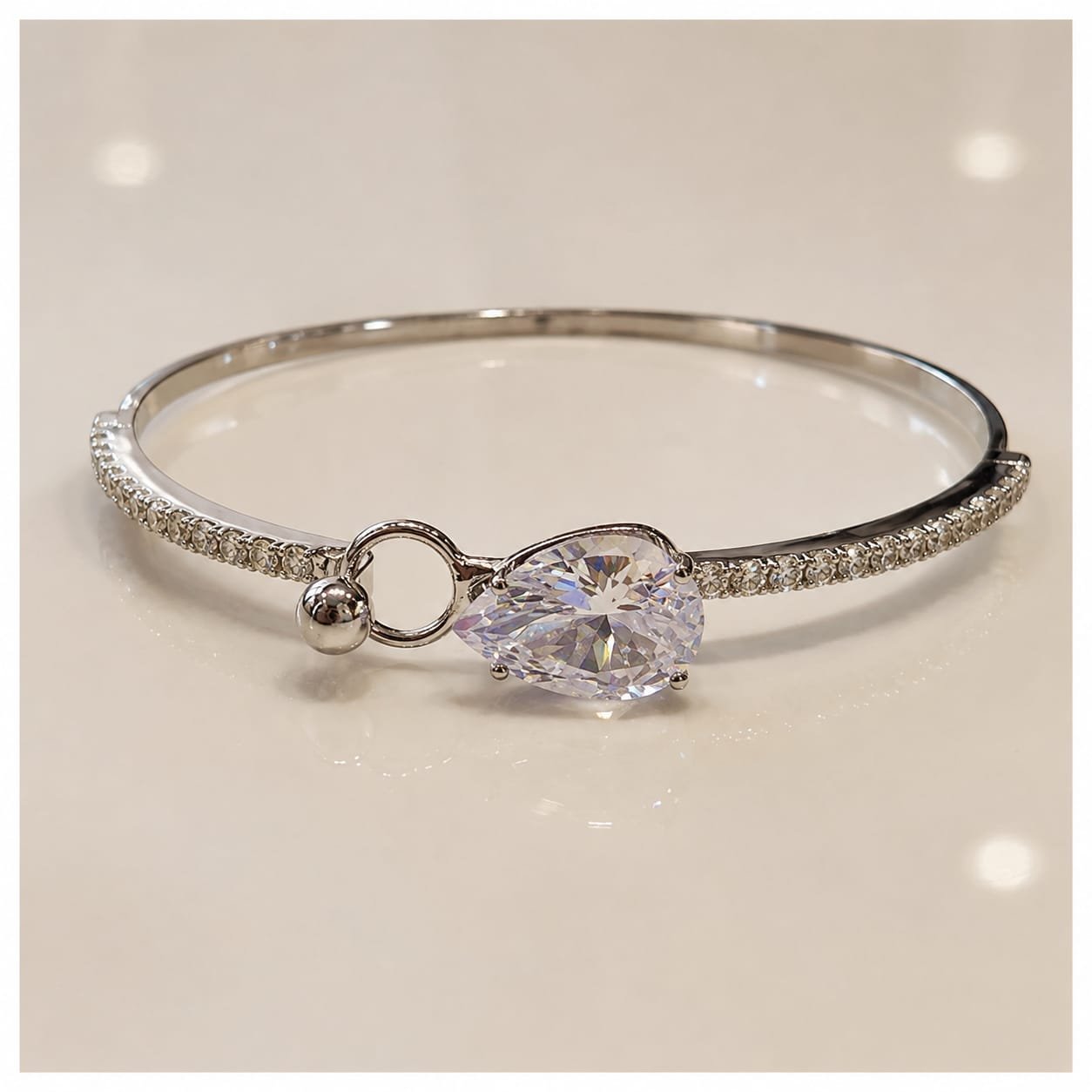 Silver-toned bypass bangle bracelet featuring a prominent, faceted central stone.