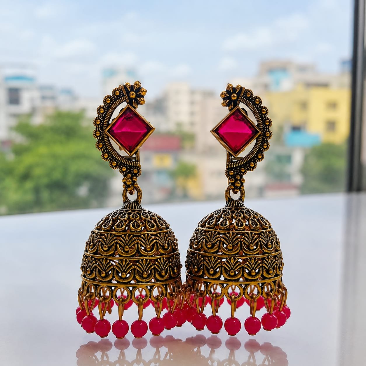 A pair of traditional Indian Jhumka earrings crafted with a vintage or antique gold-toned finish.