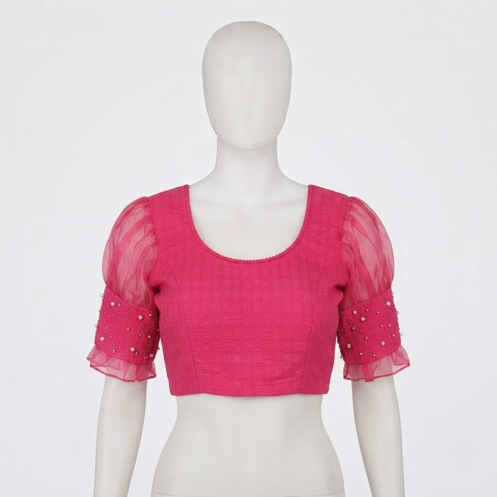 Pink jacquard saree blouse features sheer puff sleeves adorned with pearl embellishments.