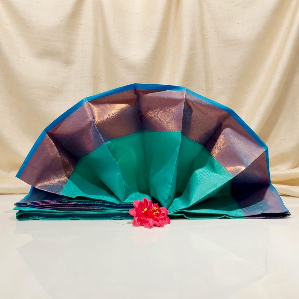 Turquoise and Purple Semi Kanchipuram silk saree features a vibrant rose gold border.