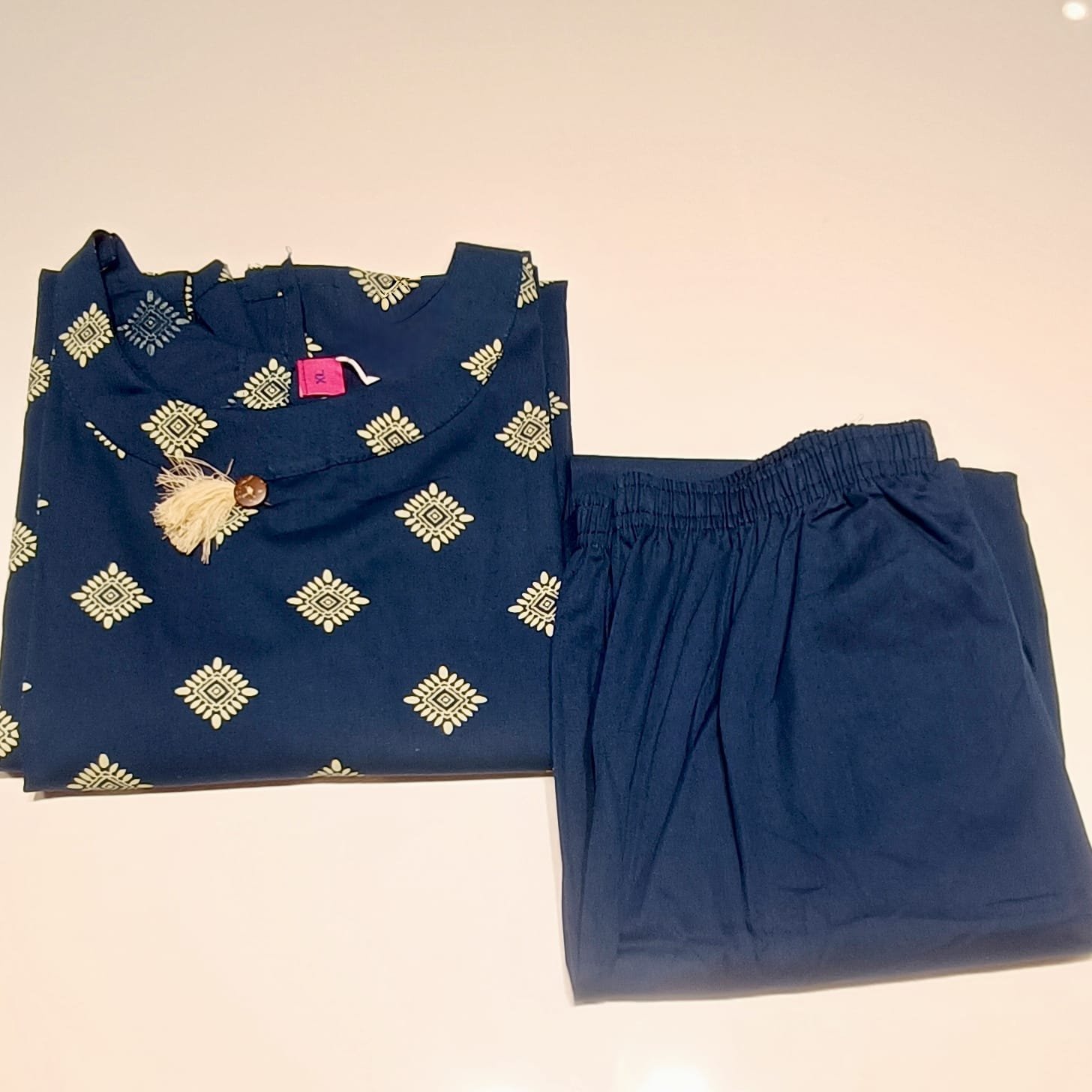 Navy blue short kurti features a gold-toned foil ethnic motif print and a functional button neckline detail.